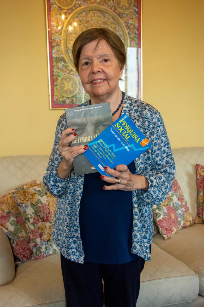 A vasta obra de Cecília Minayo tornou-se referência para as ciências sociais e a saúde coletiva; em suas mãos, dois exemplos: “De ferro e flexíveis” e “Pesquisa social: teoria, método e criatividade” – Foto: Eduardo de Oliveira